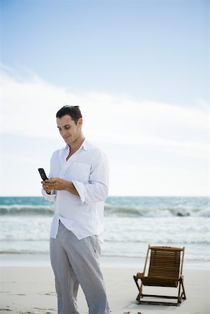 simsearch:633-01713848,k - Jeune homme à l'aide de téléphone portable sur la plage Photographie de stock - Premium Libres de Droits, Code: 633-01714441