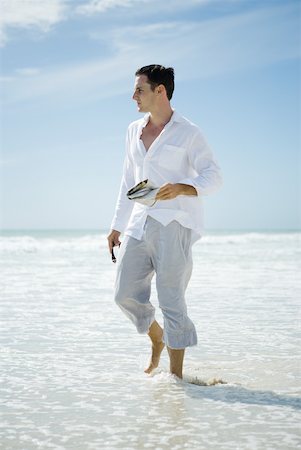 summer beach break - Young man walking through surf, looking away Stock Photo - Premium Royalty-Free, Code: 633-01714443