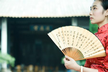 simsearch:633-01714691,k - Young woman wearing traditional Chinese clothing, holding fan, looking up Foto de stock - Royalty Free Premium, Número: 633-01714639