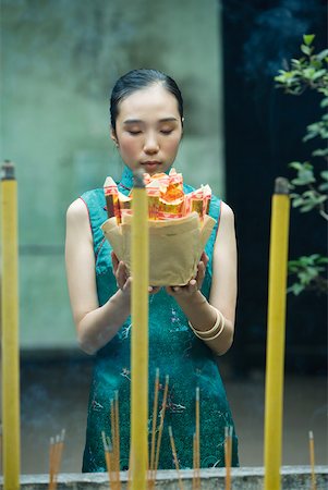 simsearch:633-01714691,k - Young woman standing in temple courtyard, holding up religious offering, eyes closed Foto de stock - Royalty Free Premium, Número: 633-01714680