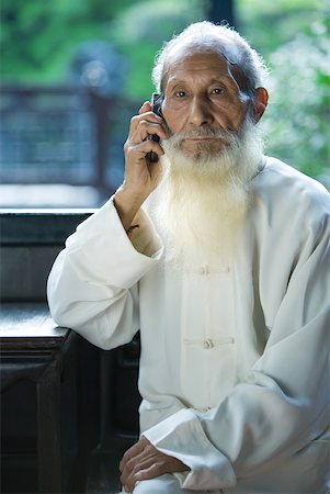 elderly on cellphone - Elderly man wearing traditional Chinese clothing, using cell phone Stock Photo - Premium Royalty-Free, Code: 633-01714712