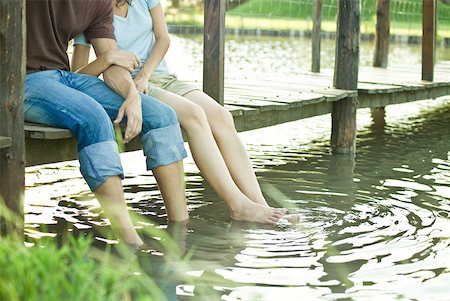 Couple sitting on dock, dangling legs in water, chest down Stock Photo - Premium Royalty-Free, Code: 633-01714943