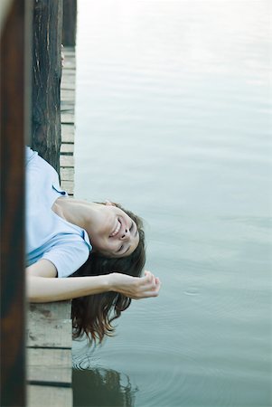 Woman lying on dock with head hanging off edge, smiling Stock Photo - Premium Royalty-Free, Code: 633-01714951