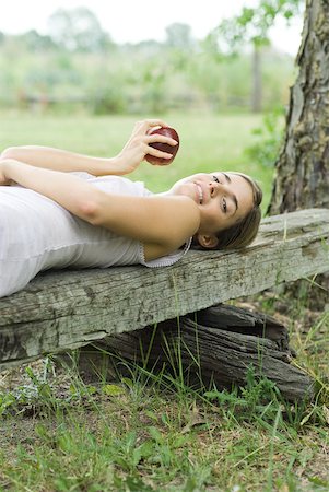 simsearch:633-01715082,k - Woman lying on piece of wood, holding apple, looking at camera Stock Photo - Premium Royalty-Free, Code: 633-01715030