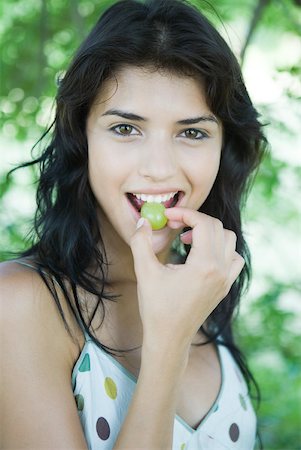 simsearch:693-06021794,k - Young woman biting into grape, looking at camera Stock Photo - Premium Royalty-Free, Code: 633-01715063