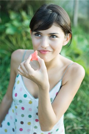 Young woman eating piece of fruit, smiling, high angle view Stock Photo - Premium Royalty-Free, Code: 633-01715085