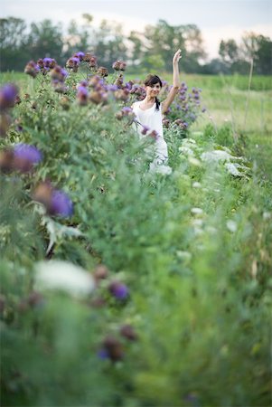 Jeune femme debout dans le jardin de la fleur, en agitant, à mi distance Photographie de stock - Premium Libres de Droits, Code: 633-01715098