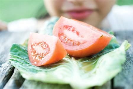 Slices of tomato, woman in background Stock Photo - Premium Royalty-Free, Code: 633-01715091
