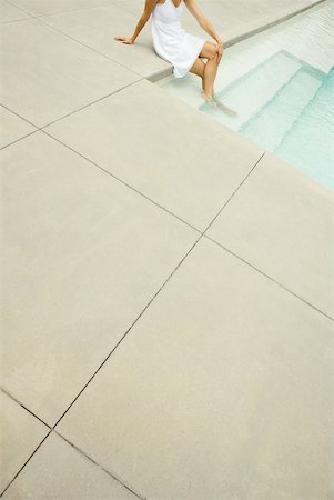 Woman sitting on edge of pool, feet in water, high angle view, cropped Stock Photo - Premium Royalty-Free, Code: 633-01715154