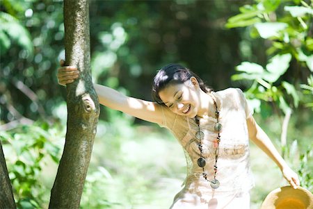 simsearch:633-01714195,k - Young woman swinging on tree trunk, smiling Stock Photo - Premium Royalty-Free, Code: 633-01715235