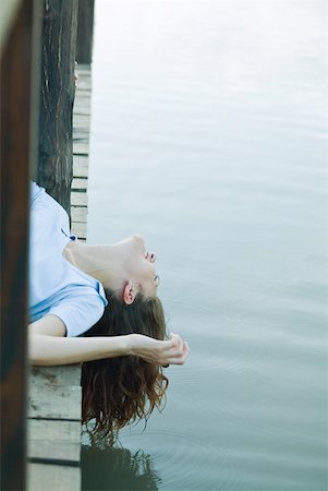 Woman lying on dock, dangling head off edge Stock Photo - Premium Royalty-Free, Code: 633-01715368