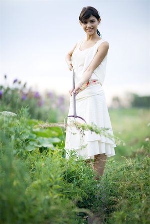 Jeune femme, enlever les mauvaises herbes dans le jardin, pleine longueur, souriant à la caméra Photographie de stock - Premium Libres de Droits, Code: 633-01715513