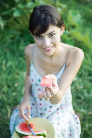 simsearch:633-01572611,k - Young woman holding up piece of watermelon, smiling at camera Stock Photo - Premium Royalty-Free, Code: 633-01715528