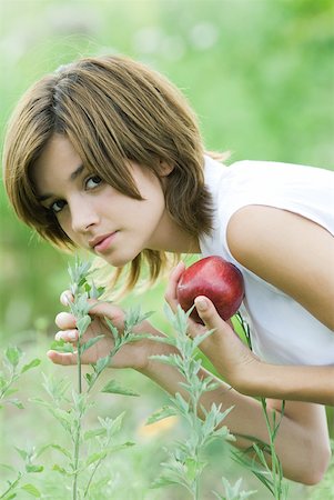 simsearch:633-01715082,k - Young woman smelling plant, holding apple Stock Photo - Premium Royalty-Free, Code: 633-01715534