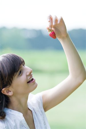 simsearch:633-01715082,k - Young woman holding up strawberry Stock Photo - Premium Royalty-Free, Code: 633-01715537