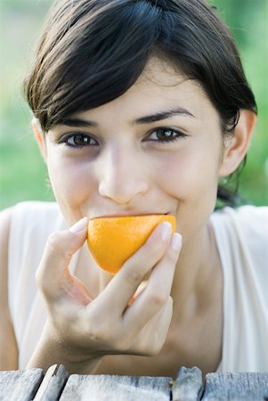 simsearch:633-01715082,k - Woman eating slice of orange, smiling at camera, close-up Stock Photo - Premium Royalty-Free, Code: 633-01715546