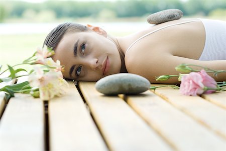 simsearch:633-02128630,k - Woman lying on deck with hot stone on back surrounded by flowers and stones Foto de stock - Sin royalties Premium, Código: 633-01715555