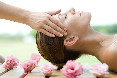 Woman lying on deck, surrounded with flowers, having head massage Stock Photo - Premium Royalty-Free, Code: 633-01715586