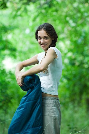 simsearch:633-01714076,k - Young camper rolling up sleeping bag, smiling at camera Stock Photo - Premium Royalty-Free, Code: 633-01715639