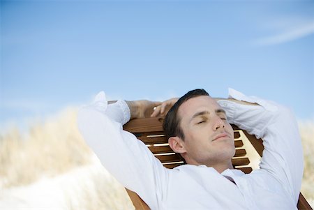 Young man sitting on deckchair, eyes closed Stock Photo - Premium Royalty-Free, Code: 633-01715659