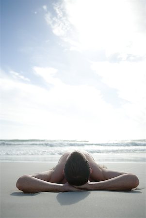 simsearch:633-01713848,k - Jeune homme couché sur la plage avec les mains derrière la tête Photographie de stock - Premium Libres de Droits, Code: 633-01715674