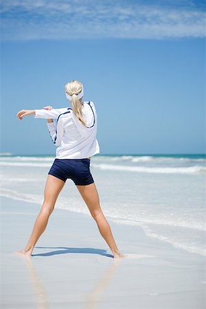 Young woman on beach, stretching, rear view Stock Photo - Premium Royalty-Free, Code: 633-01715671