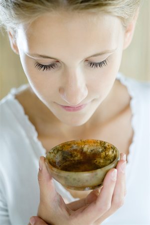 Woman holding up small bowl to nose, close-up Stock Photo - Premium Royalty-Free, Code: 633-01715709