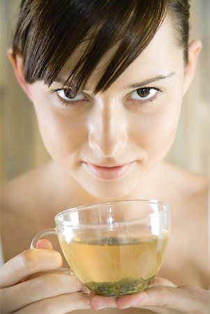 Young woman holding cup of herbal tea, looking at camera, close-up Foto de stock - Sin royalties Premium, Código: 633-01715748