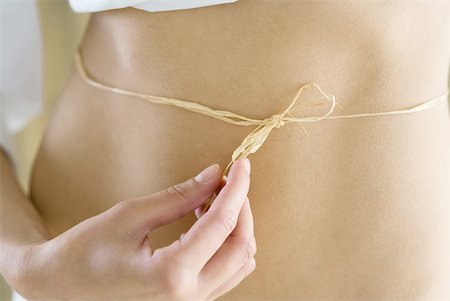 Young woman with piece of raffia tied around waist, cropped Stock Photo - Premium Royalty-Free, Code: 633-01715751