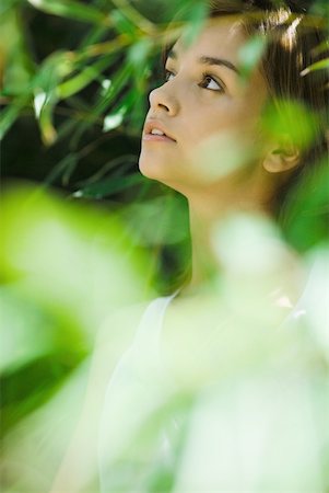 simsearch:633-02345793,k - Young woman standing in thick foliage, looking away Stock Photo - Premium Royalty-Free, Code: 633-01715888