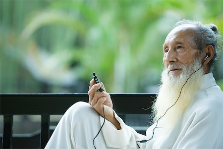 Elderly man in traditional Chinese clothing listening to MP3 player Stock Photo - Premium Royalty-Free, Code: 633-01715904