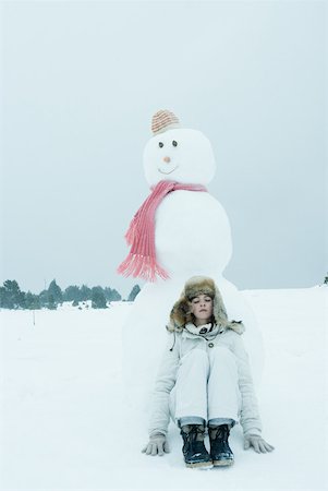 Teen girl leaning against snowman Stock Photo - Premium Royalty-Free, Code: 633-01713709