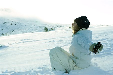 Teen girl sitting on snow, eyes closed and arms out to sides Stock Photo - Premium Royalty-Free, Code: 633-01713717