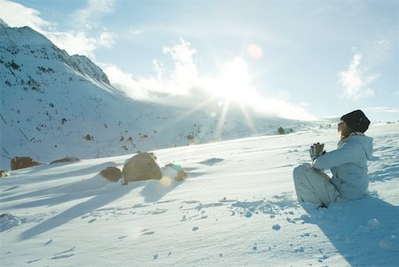 Teen girl sitting on snow in prayer position, sun shining over edge of mountain Stock Photo - Premium Royalty-Free, Code: 633-01713719