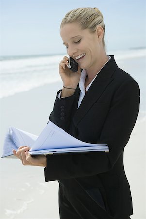 simsearch:633-01574593,k - Businesswoman using cell phone and looking at file, standing on beach, smiling Stock Photo - Premium Royalty-Free, Code: 633-01713764