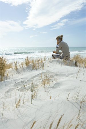 Woman sitting on dunes at beach, using cell phone and taking notes Stock Photo - Premium Royalty-Free, Code: 633-01713775