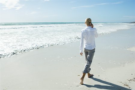 simsearch:633-01713848,k - Femme qui marche pieds nus sur la plage, à l'aide d'un téléphone cellulaire, vue arrière Photographie de stock - Premium Libres de Droits, Code: 633-01713782