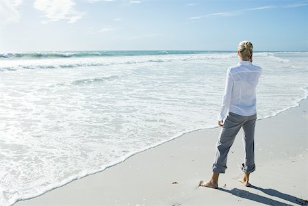 Woman standing barefoot on beach, using cell phone, rear view Stock Photo - Premium Royalty-Free, Code: 633-01713783