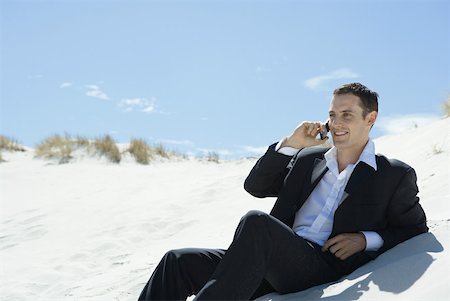simsearch:632-02745019,k - Businessman sitting on sand dune, using cell phone Stock Photo - Premium Royalty-Free, Code: 633-01713818