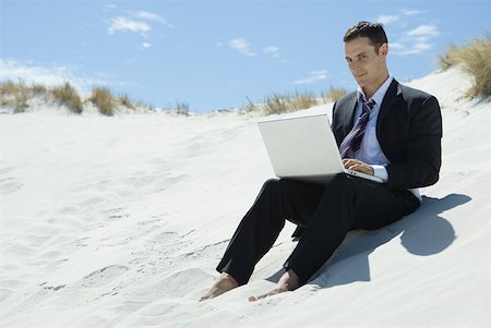 simsearch:633-01713826,k - Businessman sitting on sand dune, using laZSop Stock Photo - Premium Royalty-Free, Code: 633-01713811