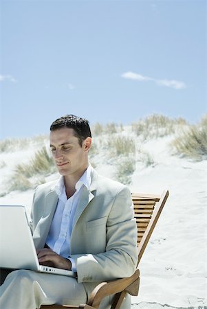 Businessman sitting in deck chair at beach, using laZSop Stock Photo - Premium Royalty-Free, Code: 633-01713824