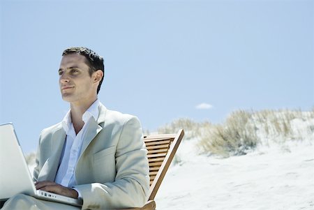 Businessman sitting in deck chair at beach, using laZSop Stock Photo - Premium Royalty-Free, Code: 633-01713825