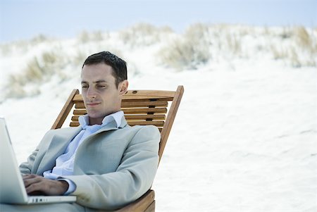 Businessman sitting in deck chair at beach, using laZSop Stock Photo - Premium Royalty-Free, Code: 633-01713826