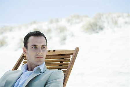 Businessman sitting in deck chair at beach, looking away Stock Photo - Premium Royalty-Free, Code: 633-01713827