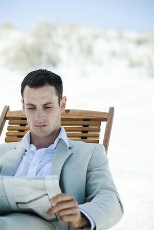Businessman sitting in deck chair at beach, reading newspaper Stock Photo - Premium Royalty-Free, Code: 633-01713829