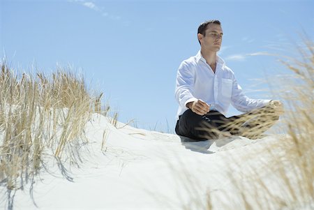 Businessman sitting on sand dune, meditating Stock Photo - Premium Royalty-Free, Code: 633-01713822