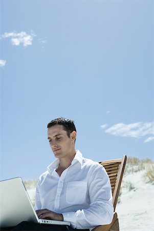 Businessman sitting in deck chair at beach, using laZSop Stock Photo - Premium Royalty-Free, Code: 633-01713823