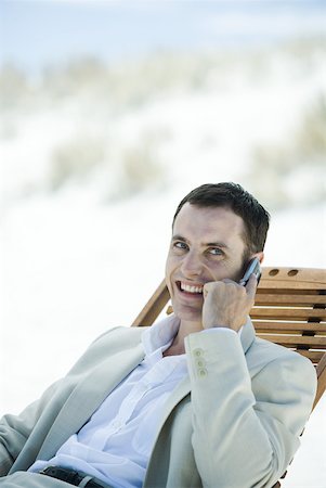 simsearch:695-03380514,k - Businessman sitting in deck chair at beach, using cell phone Fotografie stock - Premium Royalty-Free, Codice: 633-01713832