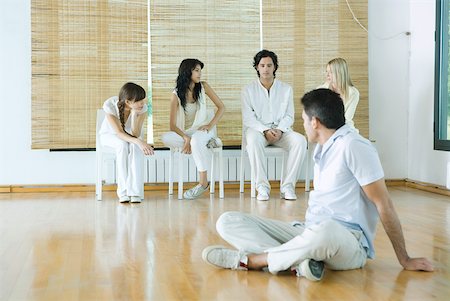 psychotherapy - Man sitting on floor, looking over shoulder at group sitting in chairs Stock Photo - Premium Royalty-Free, Code: 633-01713884