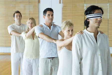 Group of adults standing single file holding onto each others' shoulders, leader blindfolded Stock Photo - Premium Royalty-Free, Code: 633-01713917